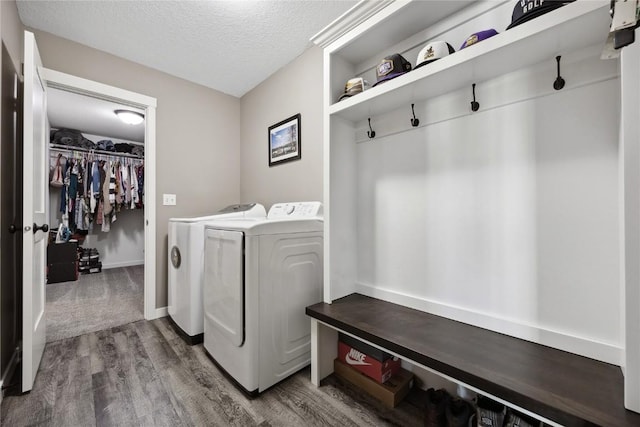 clothes washing area with wood finished floors, a textured ceiling, washing machine and dryer, and laundry area