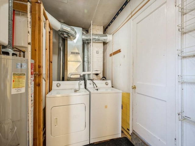 washroom featuring laundry area, water heater, and washing machine and clothes dryer