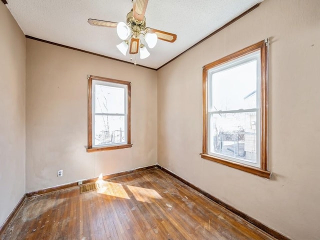 unfurnished room with baseboards, a textured ceiling, ornamental molding, and hardwood / wood-style flooring