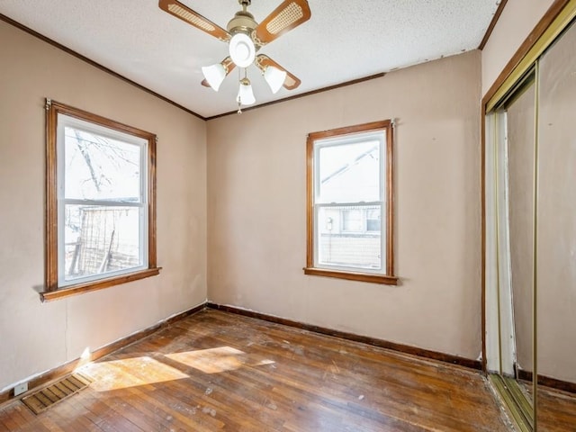 unfurnished room with visible vents, ornamental molding, a textured ceiling, and hardwood / wood-style floors