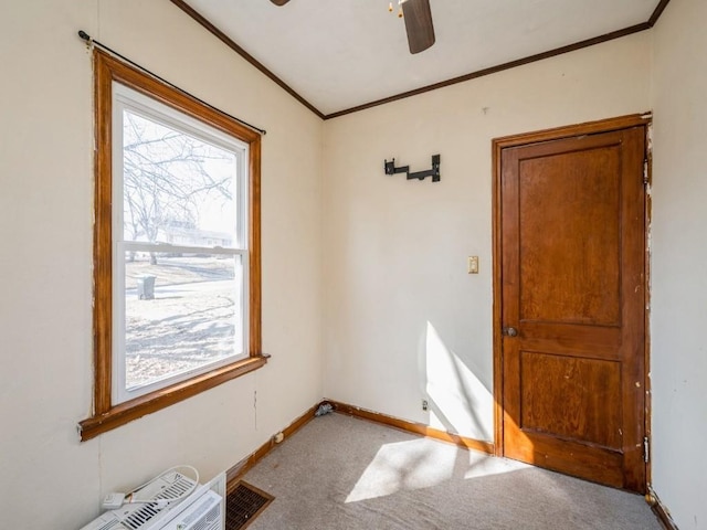 spare room featuring light carpet, plenty of natural light, crown molding, and baseboards