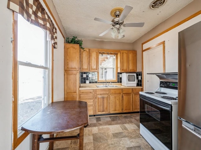 kitchen with visible vents, backsplash, freestanding refrigerator, white electric stove, and a sink