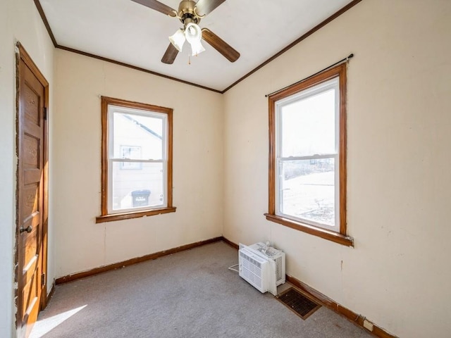 carpeted empty room featuring visible vents, a ceiling fan, baseboards, and ornamental molding