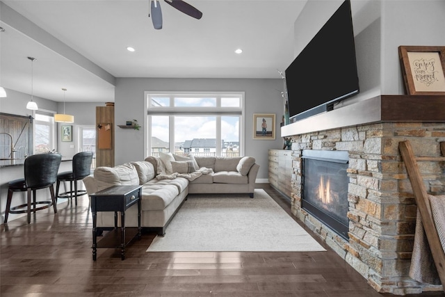 living area featuring dark wood finished floors, a stone fireplace, recessed lighting, and a ceiling fan