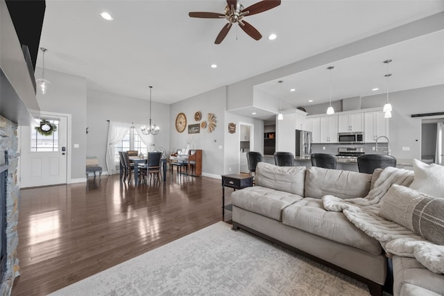 living room featuring baseboards, recessed lighting, a fireplace, ceiling fan with notable chandelier, and wood finished floors