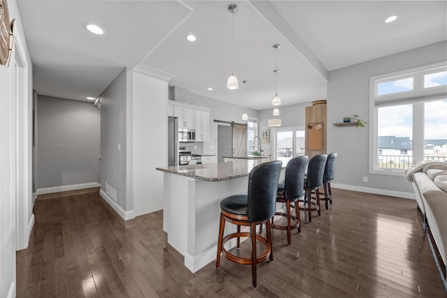 kitchen featuring a large island with sink, a wealth of natural light, dark wood-style floors, and appliances with stainless steel finishes