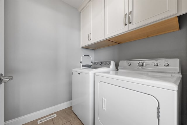 washroom with visible vents, washer and dryer, cabinet space, light tile patterned floors, and baseboards