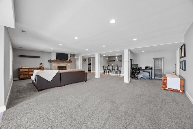 carpeted living area with visible vents, recessed lighting, a fireplace, decorative columns, and baseboards