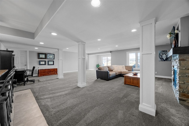 carpeted living room with a stone fireplace, recessed lighting, baseboards, and decorative columns