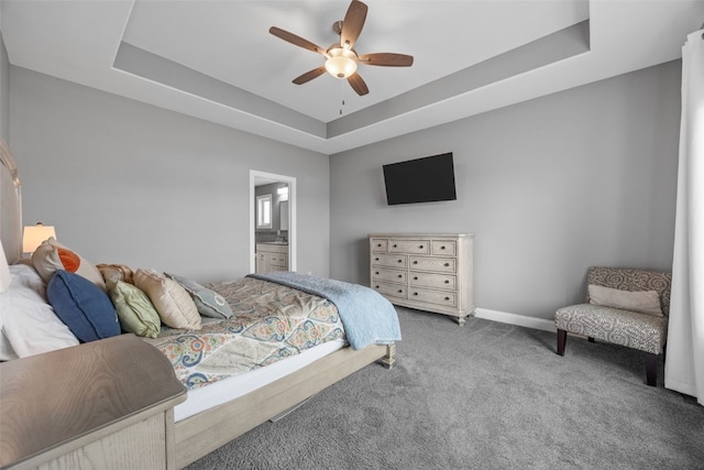 bedroom with connected bathroom, ceiling fan, baseboards, a tray ceiling, and carpet floors