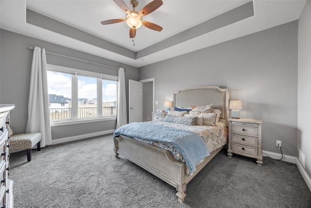 carpeted bedroom featuring a tray ceiling, baseboards, and a ceiling fan