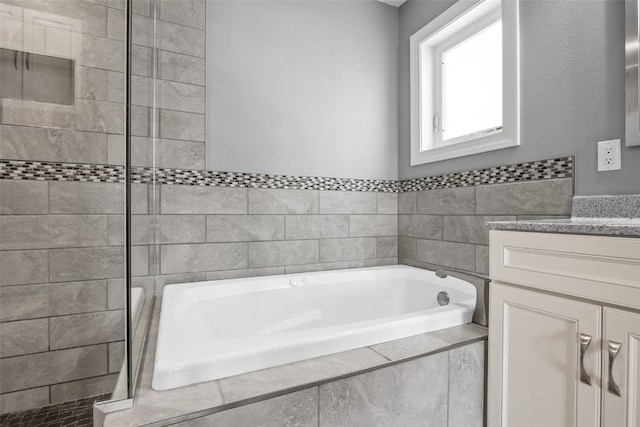 bathroom with tiled shower, a garden tub, and vanity