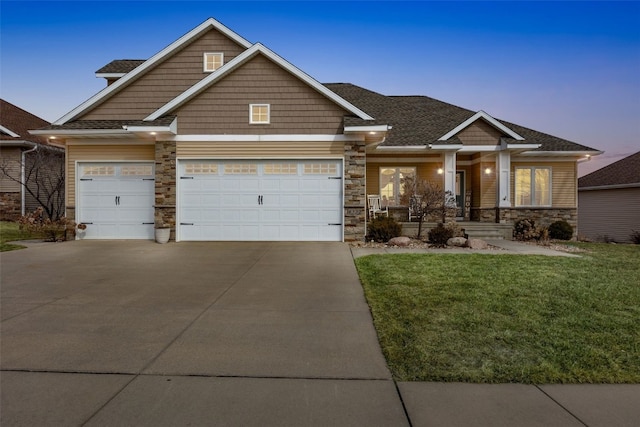 craftsman inspired home featuring a front yard, driveway, covered porch, a garage, and stone siding