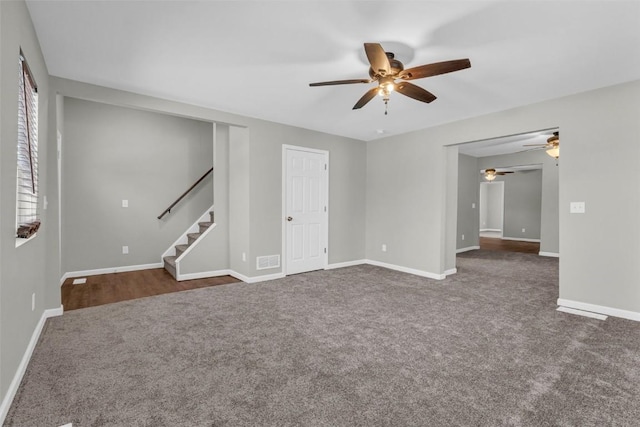 empty room featuring visible vents, baseboards, ceiling fan, stairs, and dark colored carpet