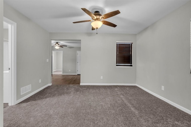 unfurnished room with visible vents, baseboards, and dark carpet