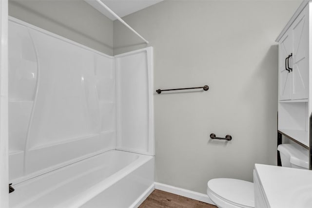 bathroom with vanity, wood finished floors, baseboards, bathtub / shower combination, and toilet