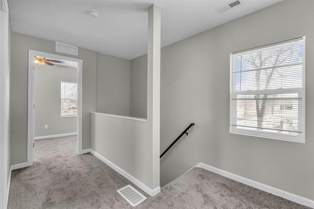 hall featuring carpet flooring, an upstairs landing, and visible vents