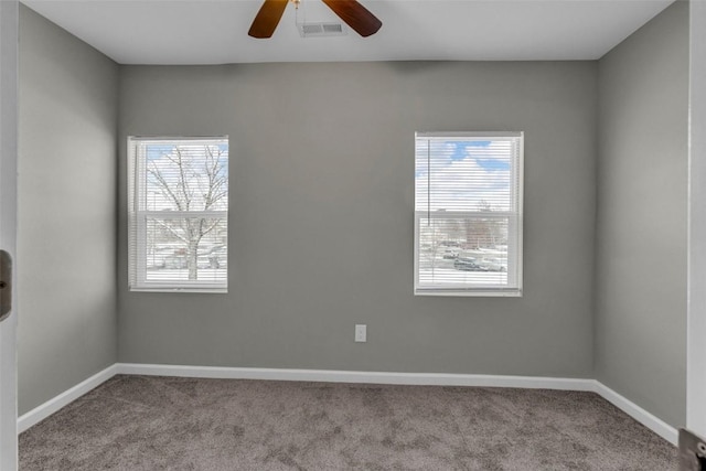 carpeted empty room featuring ceiling fan, a healthy amount of sunlight, visible vents, and baseboards