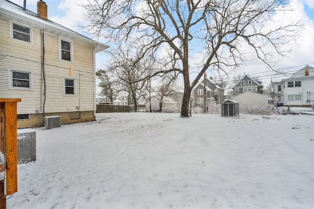 yard layered in snow featuring a residential view and central AC unit