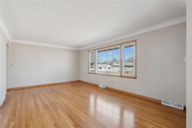 spare room featuring light wood-style flooring, baseboards, and visible vents