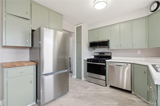 kitchen with stainless steel appliances, green cabinets, and light countertops