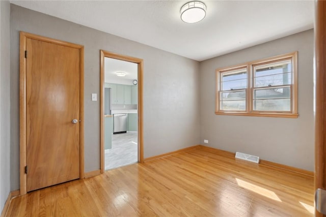 unfurnished room with visible vents, light wood-style flooring, and baseboards