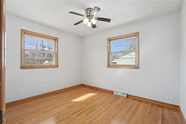 spare room featuring a wealth of natural light, visible vents, baseboards, and light wood-style flooring