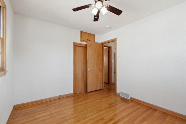 empty room with light wood finished floors, visible vents, ceiling fan, and baseboards