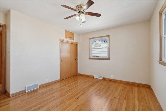 unfurnished bedroom featuring light wood-style flooring, baseboards, visible vents, and a closet