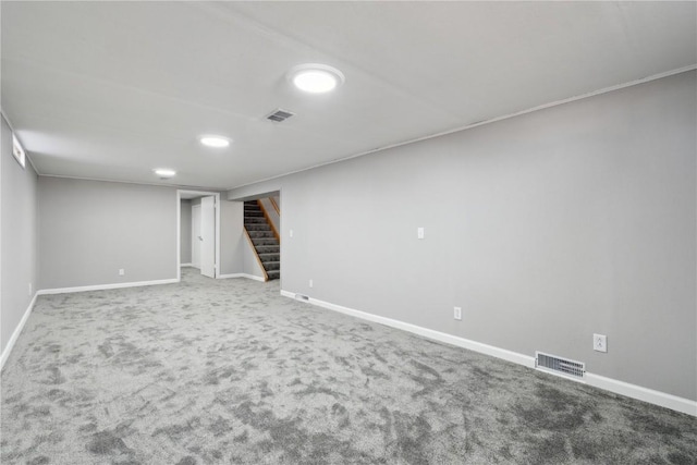 finished basement with visible vents, baseboards, carpet flooring, and stairs