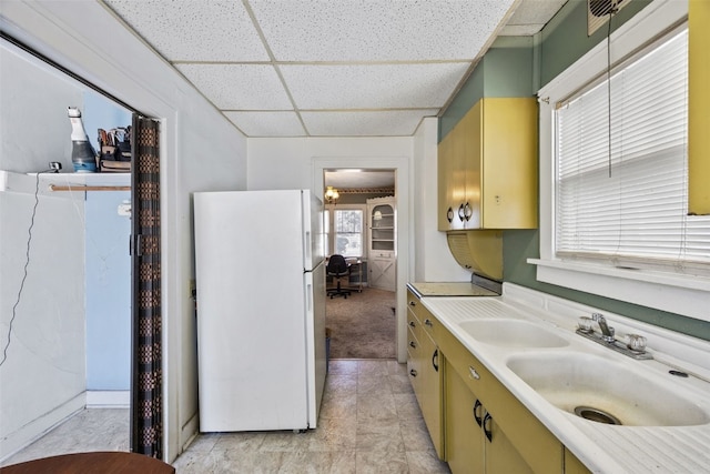 kitchen featuring visible vents, a drop ceiling, light countertops, freestanding refrigerator, and a sink