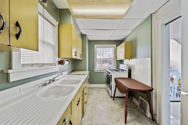 kitchen featuring visible vents, white range with gas cooktop, a sink, a drop ceiling, and light countertops