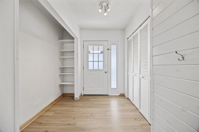 interior space featuring baseboards, light wood finished floors, and a textured ceiling