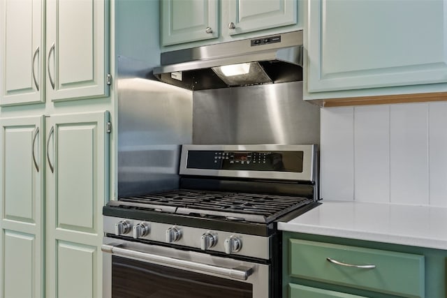 kitchen featuring green cabinets, light countertops, gas stove, and under cabinet range hood