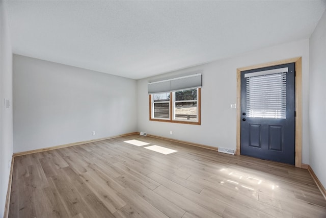 foyer with light wood finished floors, visible vents, and baseboards