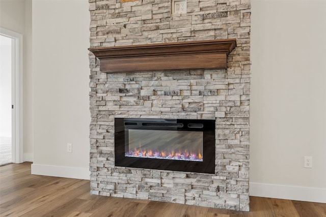 room details with a fireplace, wood finished floors, and baseboards