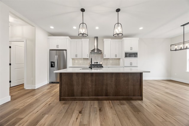 kitchen featuring an island with sink, stainless steel refrigerator with ice dispenser, a sink, wall chimney exhaust hood, and built in microwave