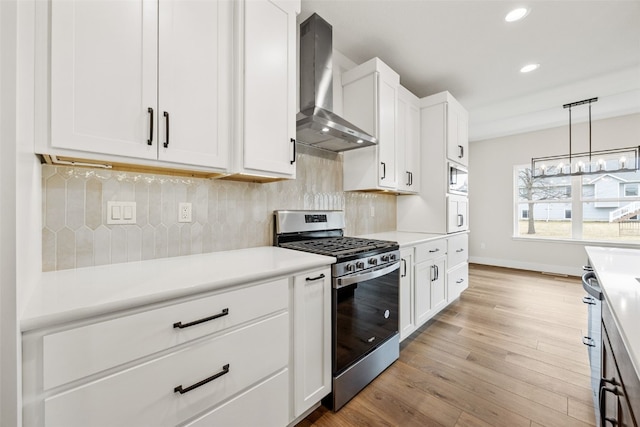 kitchen featuring light wood finished floors, tasteful backsplash, built in microwave, stainless steel gas stove, and wall chimney exhaust hood