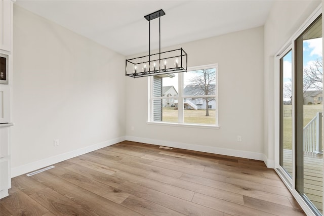 unfurnished dining area with baseboards, light wood-type flooring, and a wealth of natural light