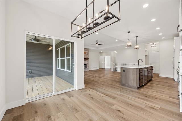 kitchen featuring a sink, open floor plan, ceiling fan, and a fireplace