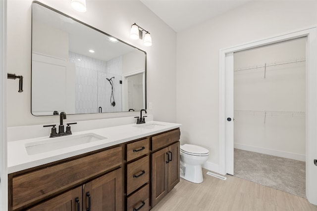 bathroom featuring a spacious closet, tiled shower, and a sink