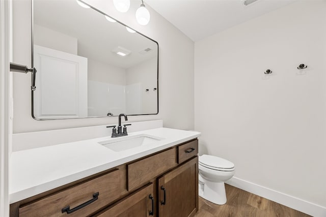 bathroom with toilet, vanity, baseboards, and wood finished floors