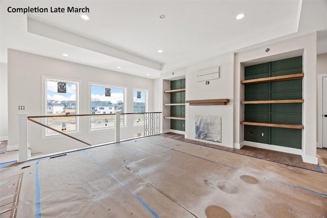 unfurnished living room with visible vents, built in shelves, a tray ceiling, recessed lighting, and a fireplace