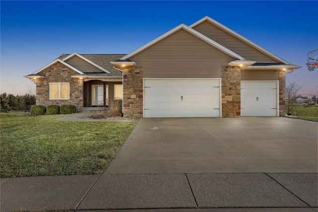 view of front of home featuring stone siding, a garage, driveway, and a front lawn