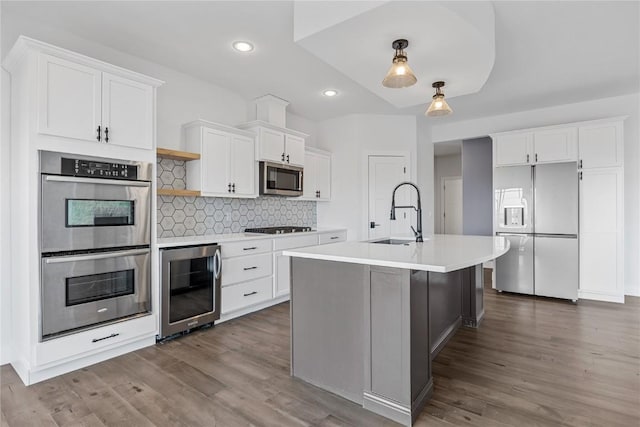 kitchen with a sink, wine cooler, light countertops, stainless steel appliances, and open shelves