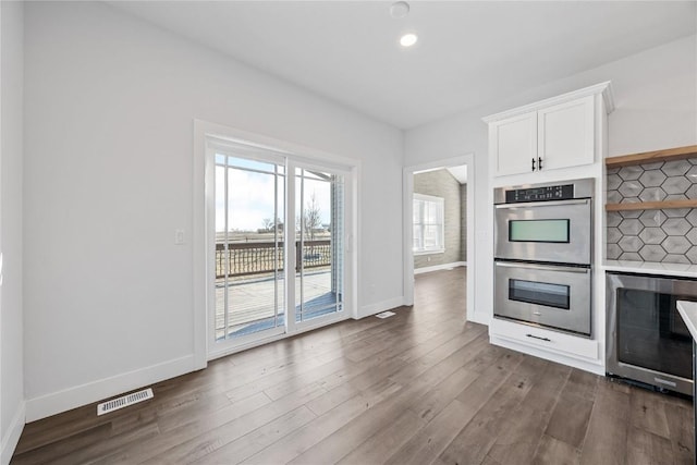 kitchen featuring visible vents, dark wood finished floors, wine cooler, white cabinets, and double oven