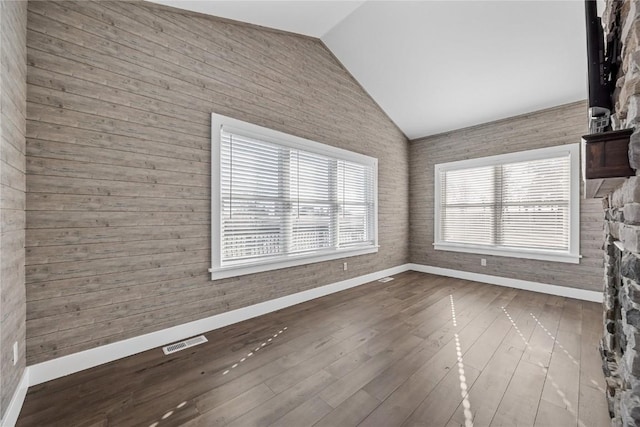 unfurnished living room featuring visible vents, baseboards, dark wood-style floors, and vaulted ceiling