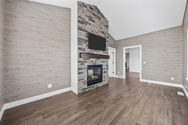 unfurnished living room featuring visible vents, high vaulted ceiling, wood finished floors, a fireplace, and baseboards