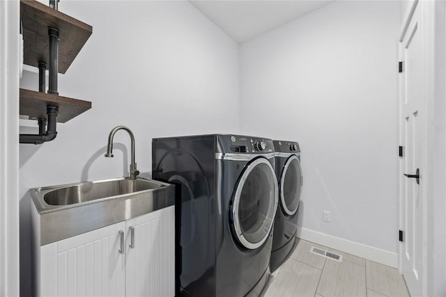 washroom featuring visible vents, baseboards, washer and dryer, cabinet space, and a sink