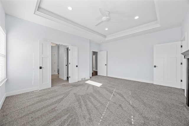 unfurnished bedroom featuring visible vents, a raised ceiling, baseboards, and carpet floors